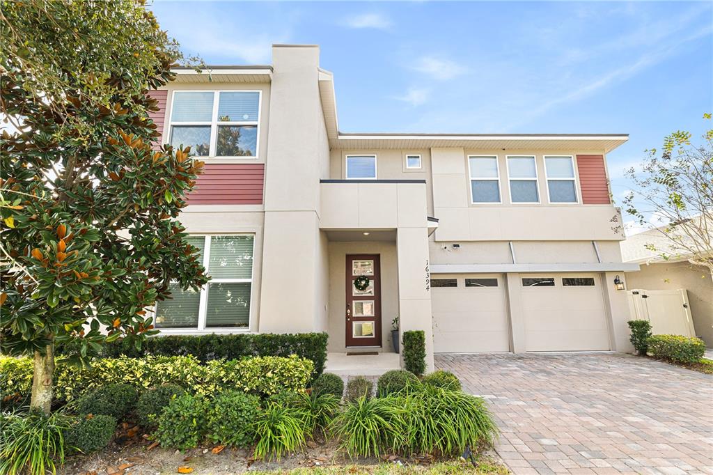 A two-story house with a beige stucco exterior, a two-car garage, and a landscaped front yard — 16394 TALIESIN STREET, WINTER GARDEN, FL