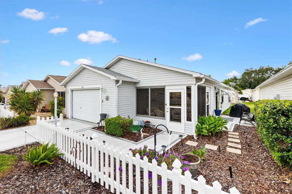 A light gray single-story house features a white picket fence, garage, and screened-in porch — 3541 ROANOKE STREET, THE VILLAGES, FL