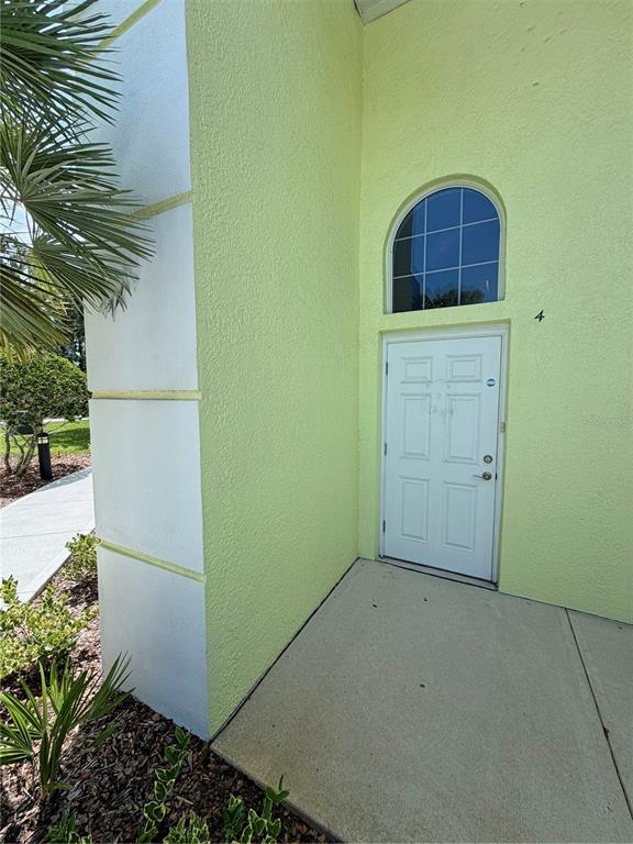 The exterior of a light green building features a white front door and arched window — 50 CYPRESS POINT PARKWAY UNIT B4, PALM COAST, FL