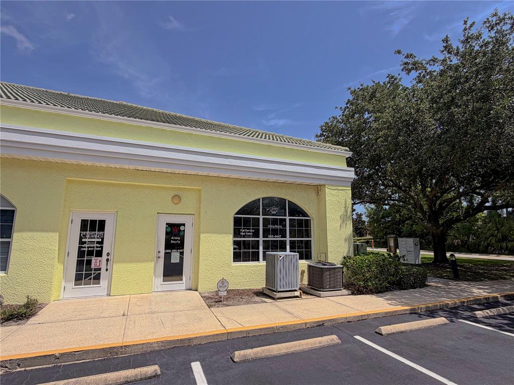 The exterior of a yellow commercial building features two glass-paned doors and a large window — 50 CYPRESS POINT PARKWAY UNIT B4, PALM COAST, FL