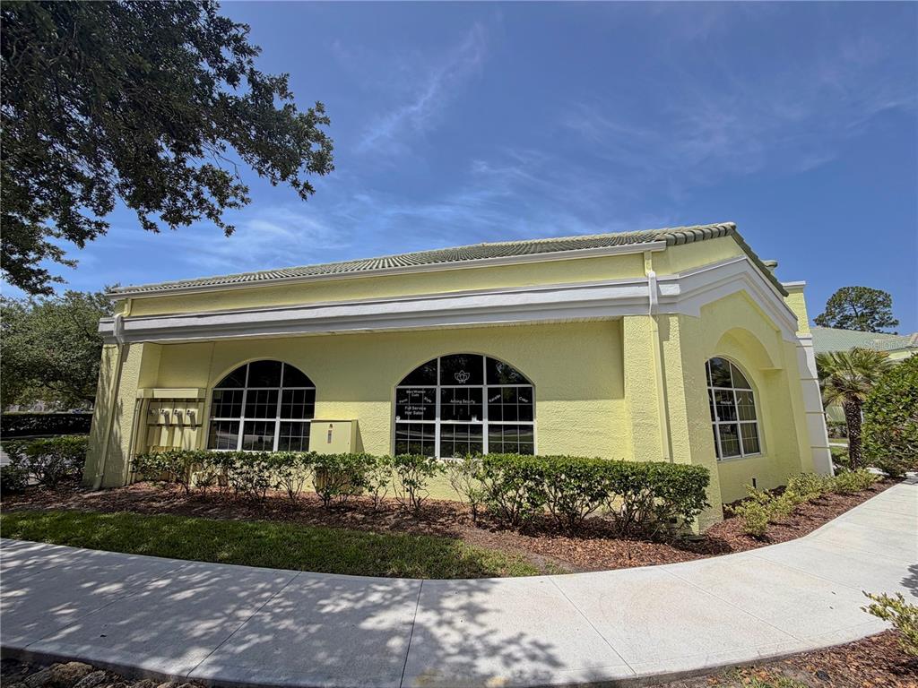 A yellow stucco commercial building with arched windows and a sidewalk in the foreground — 50 CYPRESS POINT PARKWAY UNIT B4, PALM COAST, FL