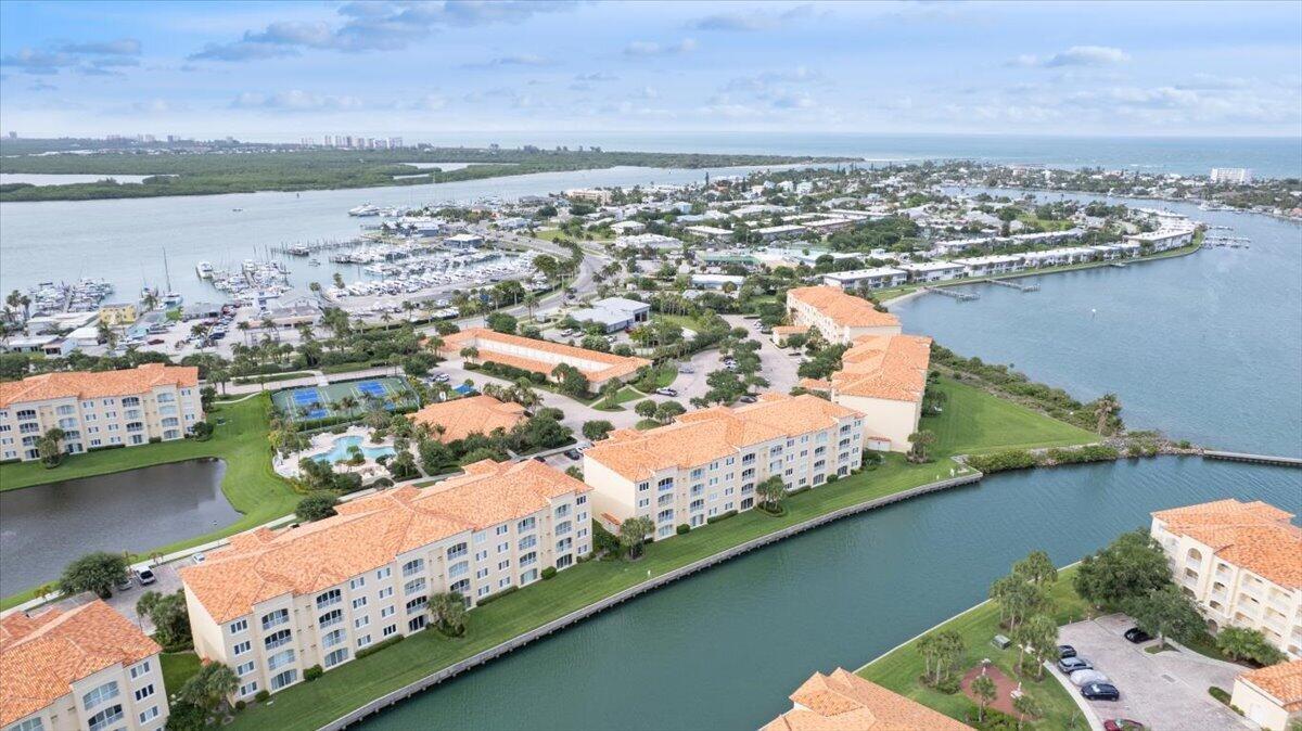 An aerial view of a waterfront residential complex with orange-tiled roofs and a nearby marina — 5 E Harbour Isle Dr Drive E # 103, Fort Pierce FL 34949, FORT PIERCE, FL