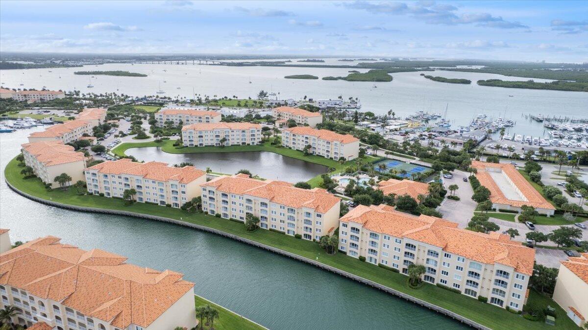 An aerial view of a waterfront apartment complex with orange-tiled roofs and a central pond — 5 E Harbour Isle Dr Drive E # 103, Fort Pierce FL 34949, FORT PIERCE, FL