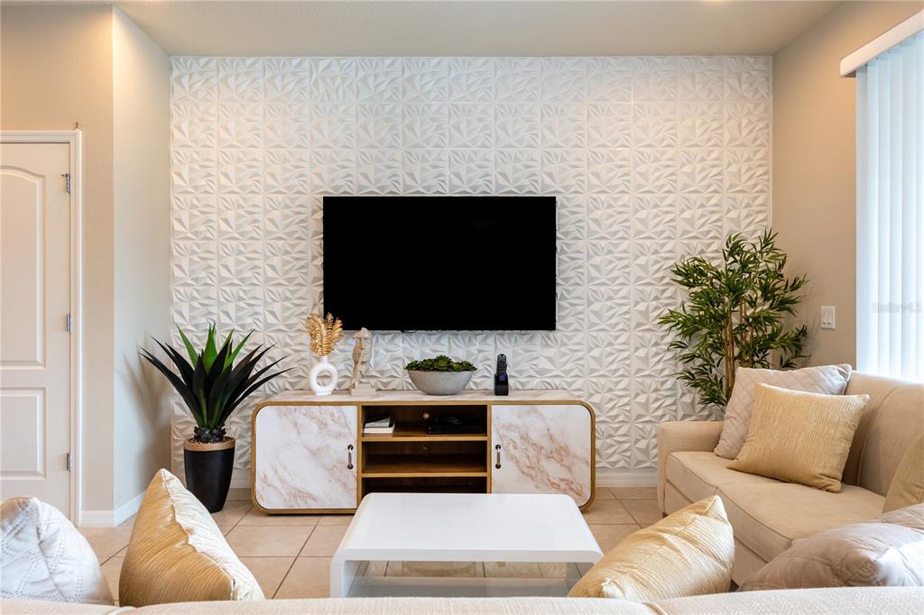 A living room features a white 3D textured accent wall, a television, and a marble-patterned console — 8894 GENEVE COURT, KISSIMMEE, FL