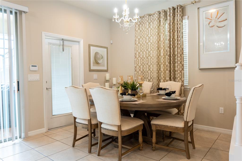 A dining room features a round wooden table with upholstered chairs under a crystal chandelier — 8894 GENEVE COURT, KISSIMMEE, FL