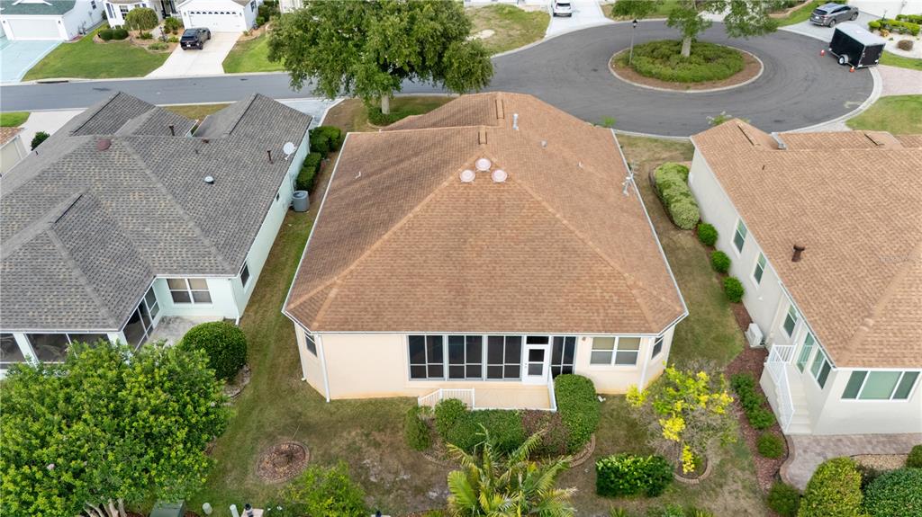 An aerial view shows the rear exterior of a suburban house with a screened-in porch — 1570 GIFFORD COURT, THE VILLAGES, FL