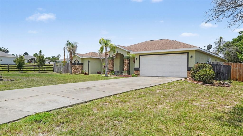 A single-story house with a two-car garage, stone accents, and a concrete driveway — 10300 SW 47TH AVENUE, OCALA, FL