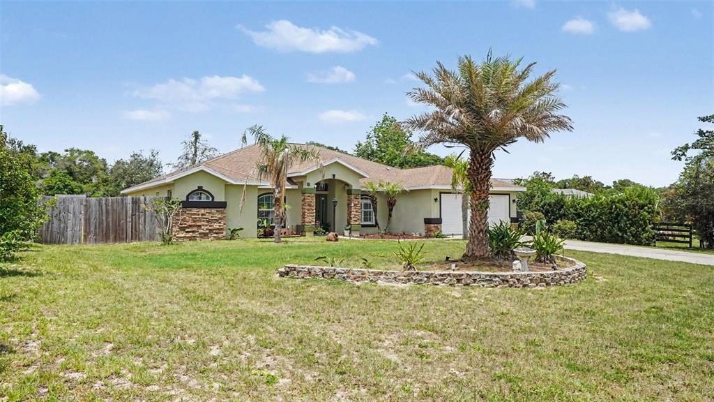 A single-story house with a stone-accented facade, a palm tree, and a stone-bordered garden — 10300 SW 47TH AVENUE, OCALA, FL