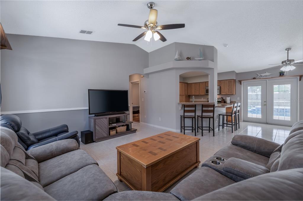 A living room with gray walls, tile floors, a television, and an open kitchen area — 2980 WINDLE LANE, SOUTH DAYTONA, FL