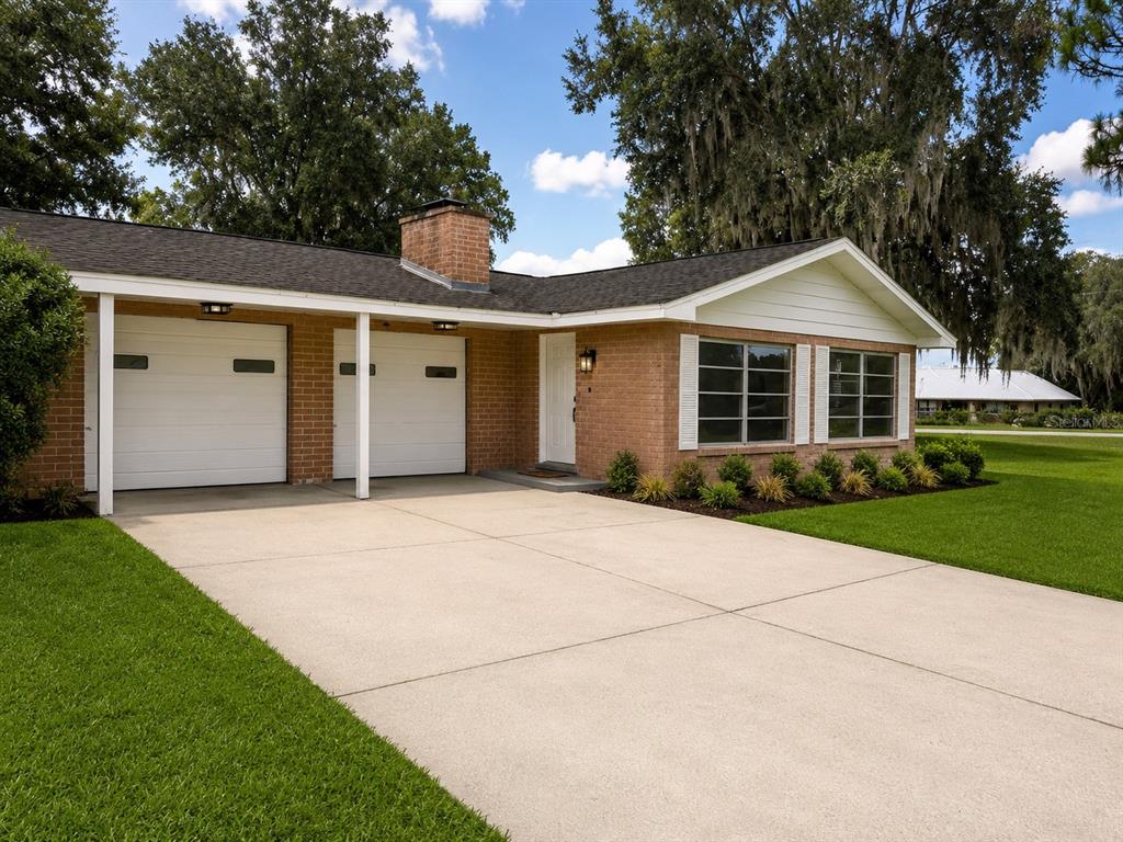 A single-story brick house features a two-car garage, a concrete driveway, and a front lawn — 13895 SE 100TH AVENUE, SUMMERFIELD, FL