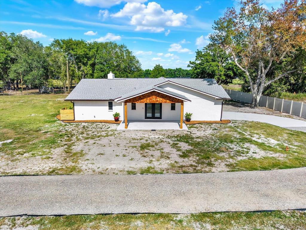 An aerial view of a white single-story house with a wood-accented front porch — 2515 RAGINS LANE, PLANT CITY, FL
