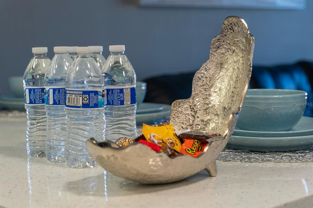 A silver decorative bowl filled with candy sits on a countertop next to water bottles — 7601 CANADA AVENUE UNIT 617, ORLANDO, FL