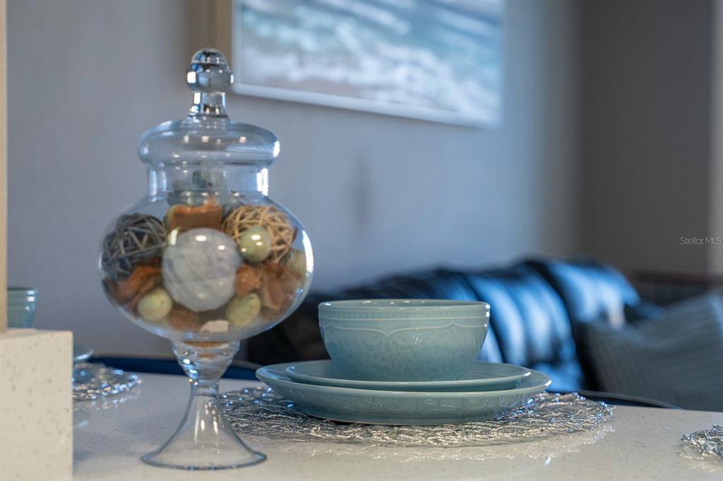 A glass decorative jar and a blue place setting sit on a white countertop — 7601 CANADA AVENUE UNIT 617, ORLANDO, FL