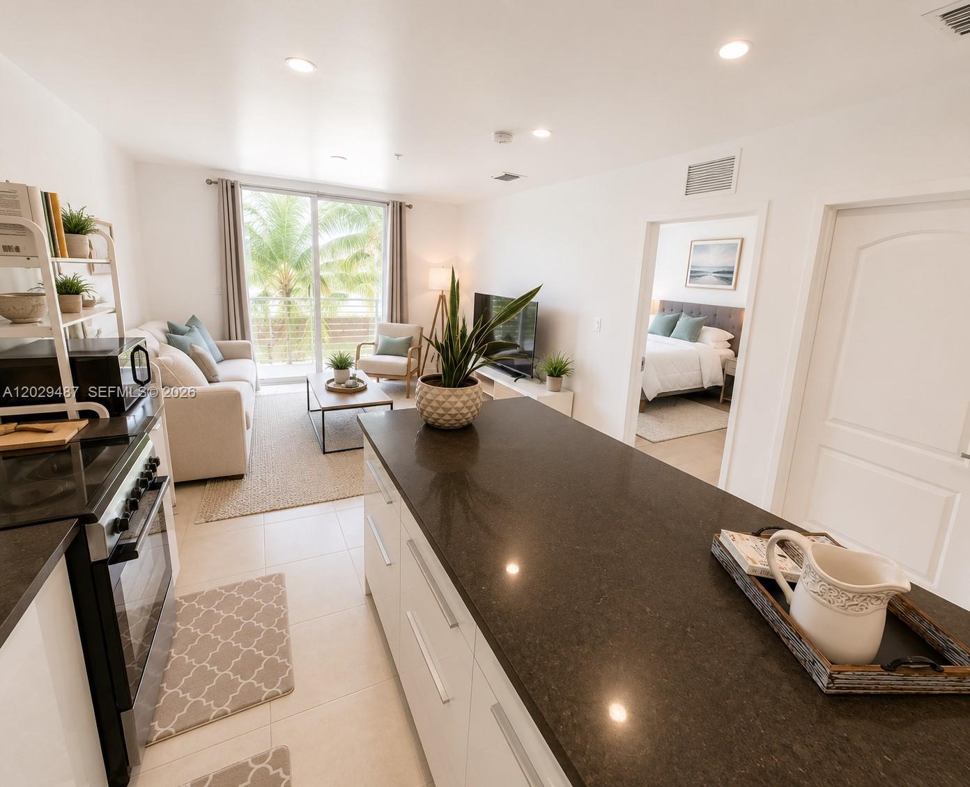A kitchen island with dark countertops overlooks a living area and a bedroom beyond — 945 Michigan Ave # 5, Miami Beach FL 33139, MIAMI BEACH, FL