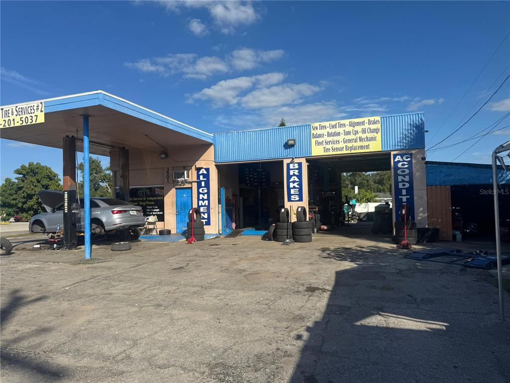 An exterior view of an automotive repair shop with service bays and stacked tires — 3501 14TH STREET W, BRADENTON, FL
