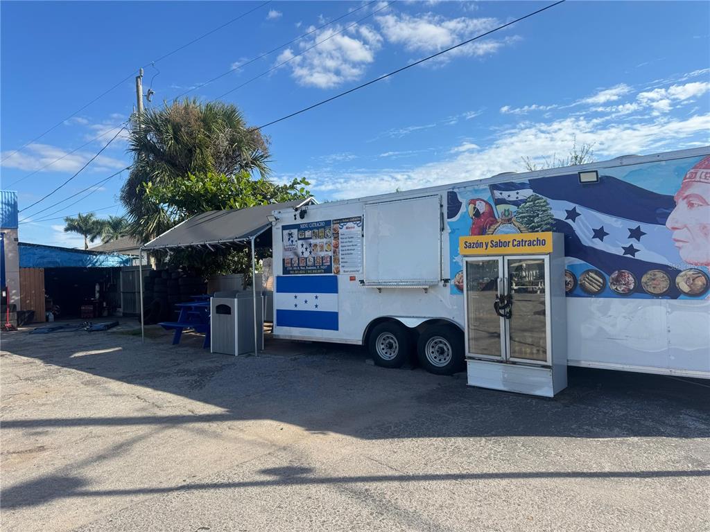 A food trailer with a Honduran flag design is parked on a gravel lot — 3501 14TH STREET W, BRADENTON, FL