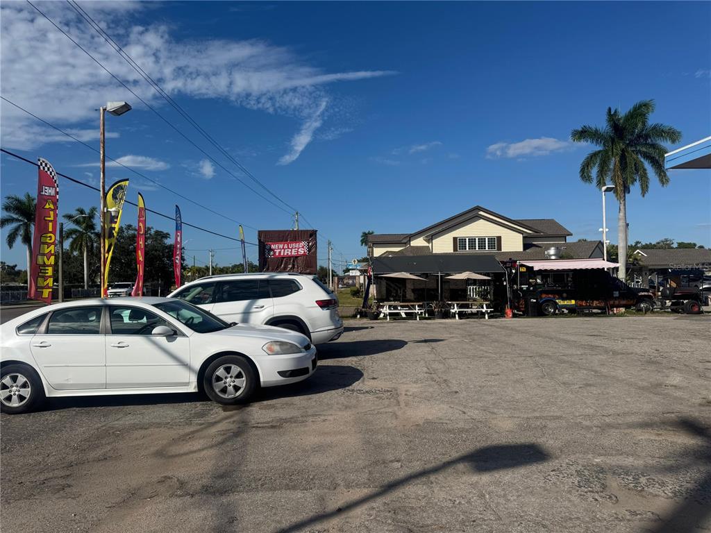 A parking lot features two white cars, a tire shop sign, and a food truck — 3501 14TH STREET W, BRADENTON, FL