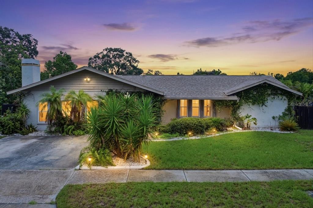 A single-story house with a gray exterior, a driveway, and landscaping at dusk — 1221 E LIME STREET, TARPON SPRINGS, FL