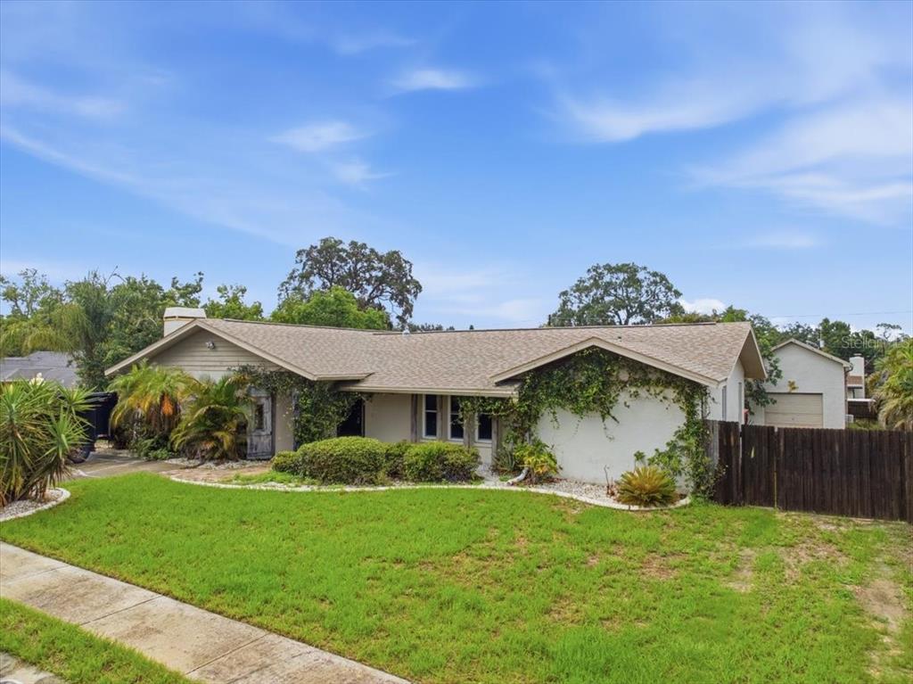 A single-story house with a light-colored exterior, a shingled roof, and climbing vines — 1221 E LIME STREET, TARPON SPRINGS, FL