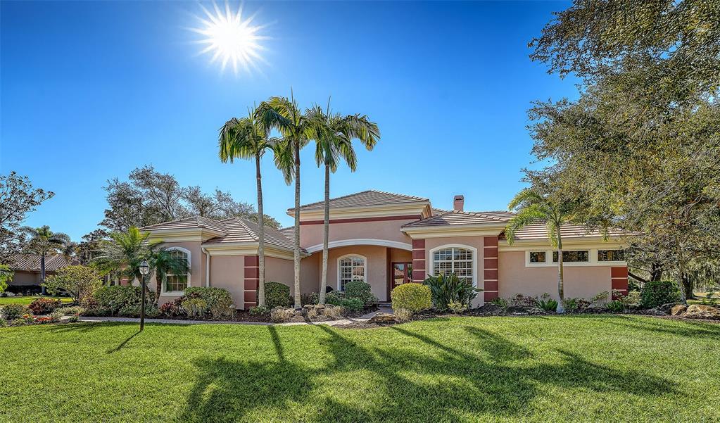 A single-story stucco house with a tiled roof and palm trees in the front yard — 7522 CONSERVATION COURT, SARASOTA, FL
