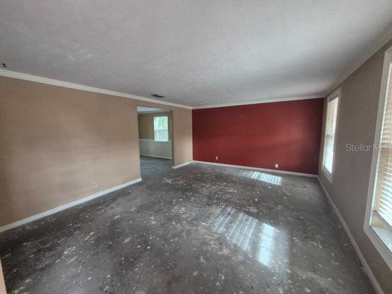 An empty room with beige and red walls, crown molding, and a bare concrete floor — 1702 KETCH PLACE, BRANDON, FL