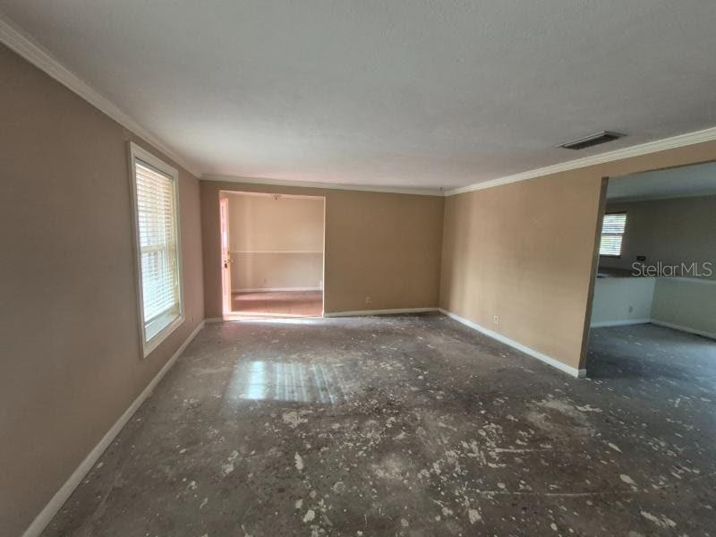 An empty room with beige walls and a concrete floor showing signs of adhesive residue — 1702 KETCH PLACE, BRANDON, FL
