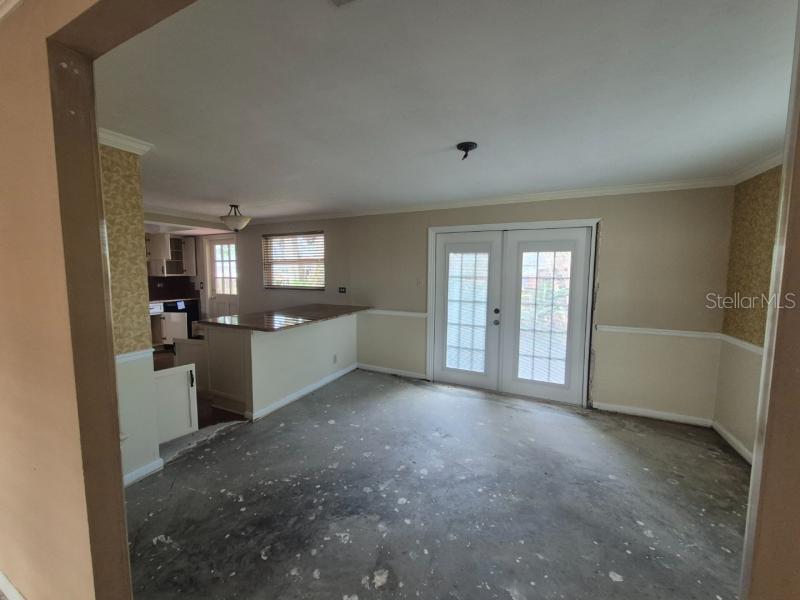 An interior view shows a room with a concrete floor, a kitchen counter, and French doors — 1702 KETCH PLACE, BRANDON, FL