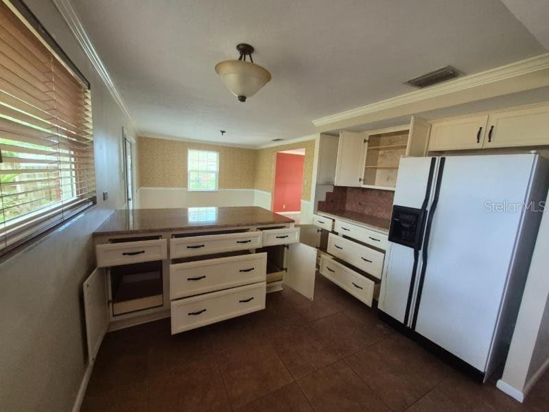 A kitchen features white cabinets with open drawers, a large refrigerator, and tile flooring — 1702 KETCH PLACE, BRANDON, FL