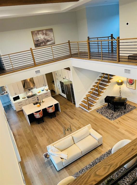 An open-concept living area features a kitchen, staircase, and loft with light wood flooring — 790 CORDOVA BOULEVARD NE, ST PETERSBURG, FL