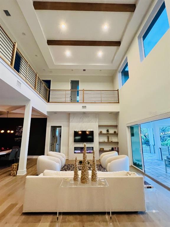 A high-ceilinged living room features wood ceiling beams, a fireplace, and a second-floor balcony — 790 CORDOVA BOULEVARD NE, ST PETERSBURG, FL