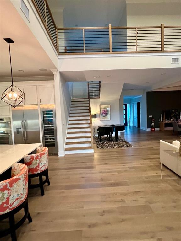 An open-concept kitchen and living area features a staircase, loft railing, and hardwood floors — 790 CORDOVA BOULEVARD NE, ST PETERSBURG, FL
