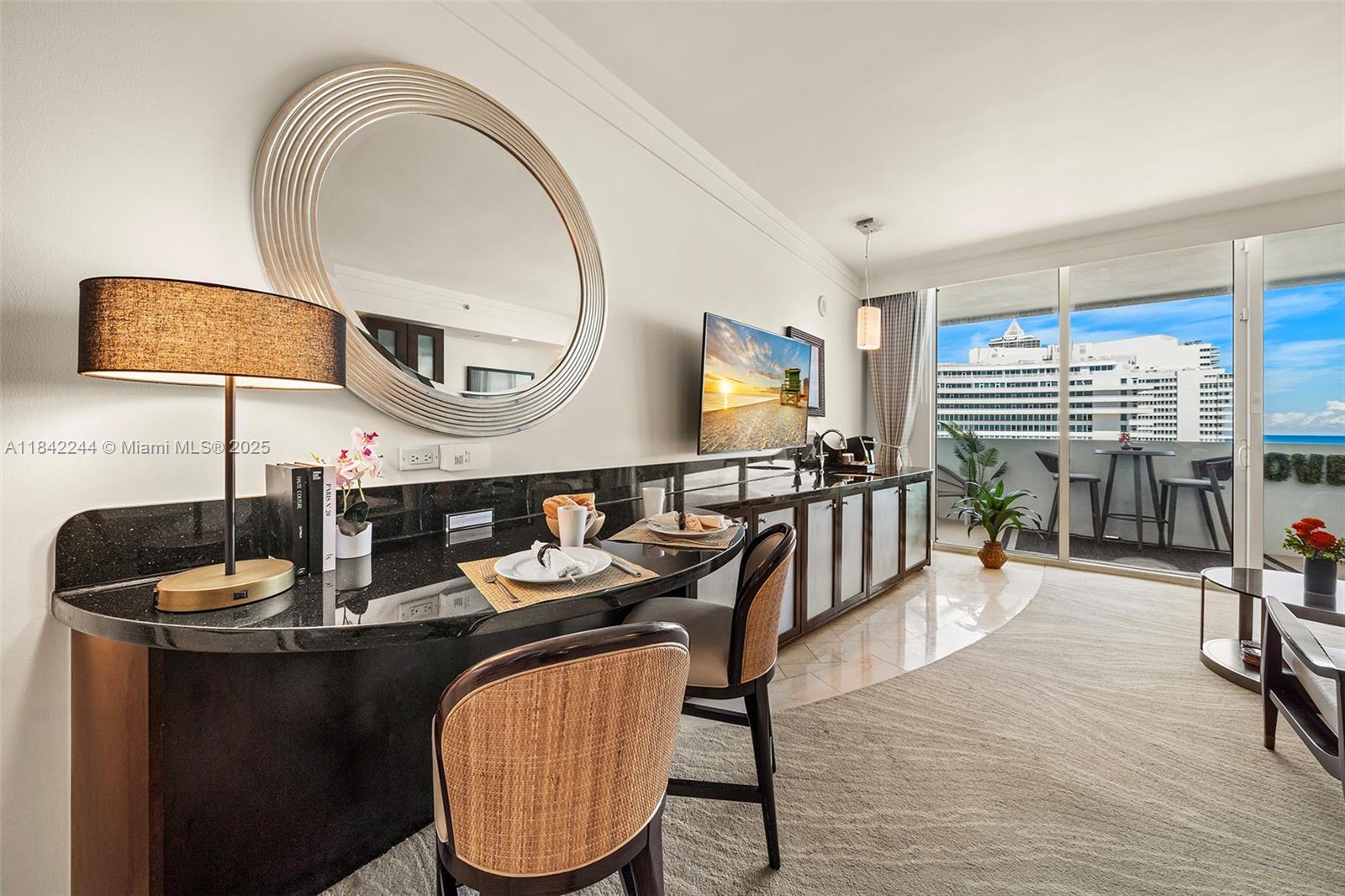 A hotel room features a curved black granite desk, two chairs, and a balcony view — 4391 Collins Ave # 802, Miami Beach FL 33140, MIAMI BEACH, FL