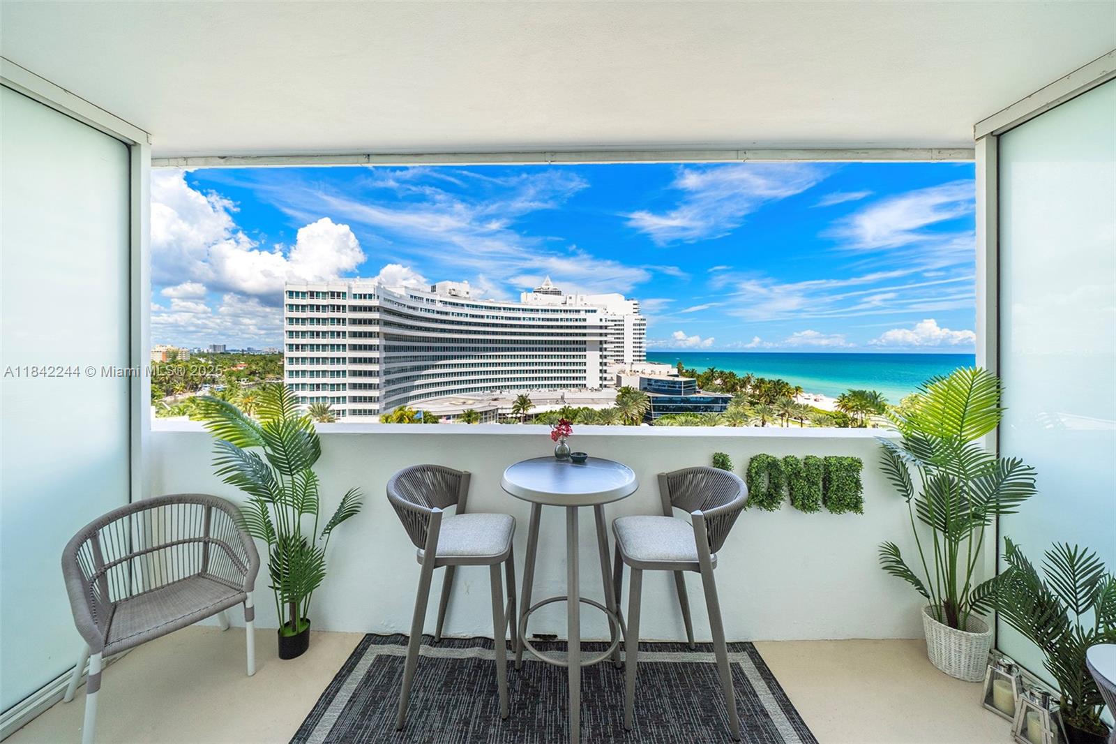 A balcony features a small table with two chairs, a side chair, and ocean views — 4391 Collins Ave # 802, Miami Beach FL 33140, MIAMI BEACH, FL