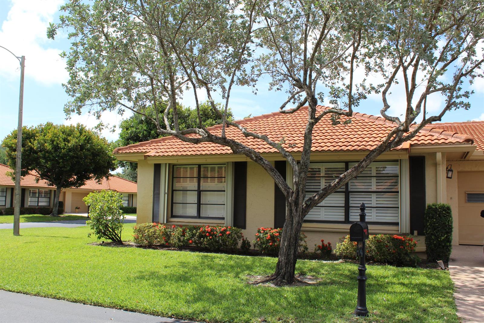 A single-story house with a terracotta tile roof, beige stucco walls, and a front yard — 4525 Nutmeg Tree Lane # A, Boynton Beach FL 33436, BOYNTON BEACH, FL