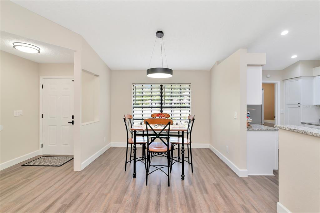 A dining area features a table with four chairs, a modern pendant light, and wood-look flooring — 6104 26TH AVENUE E, BRADENTON, FL