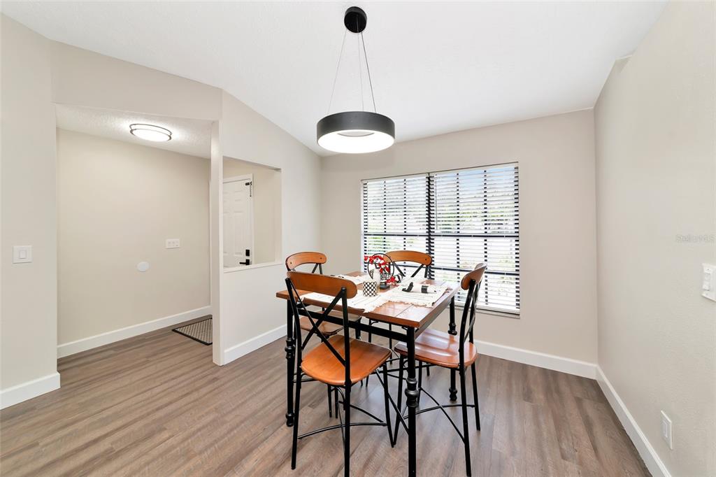 A dining area features wood-look flooring, a modern pendant light, and a wooden table set — 6104 26TH AVENUE E, BRADENTON, FL
