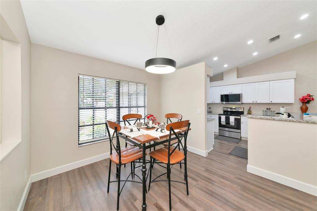 A dining area with a wood table and chairs sits adjacent to an open kitchen — 6104 26TH AVENUE E, BRADENTON, FL