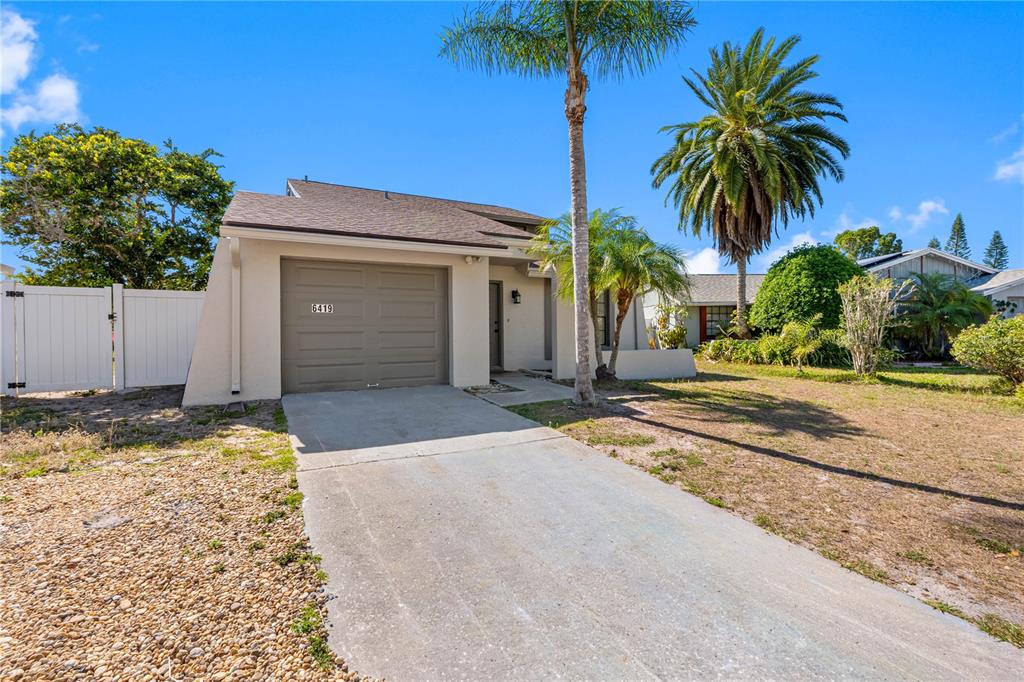 A single-story house with a tan exterior, a garage, and a palm tree in front — 6419 MONTEREY BOULEVARD, TAMPA, FL