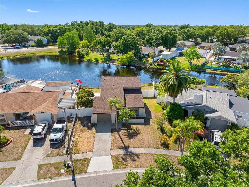 An aerial view shows a suburban house with a brown roof situated beside a lake — 6419 MONTEREY BOULEVARD, TAMPA, FL