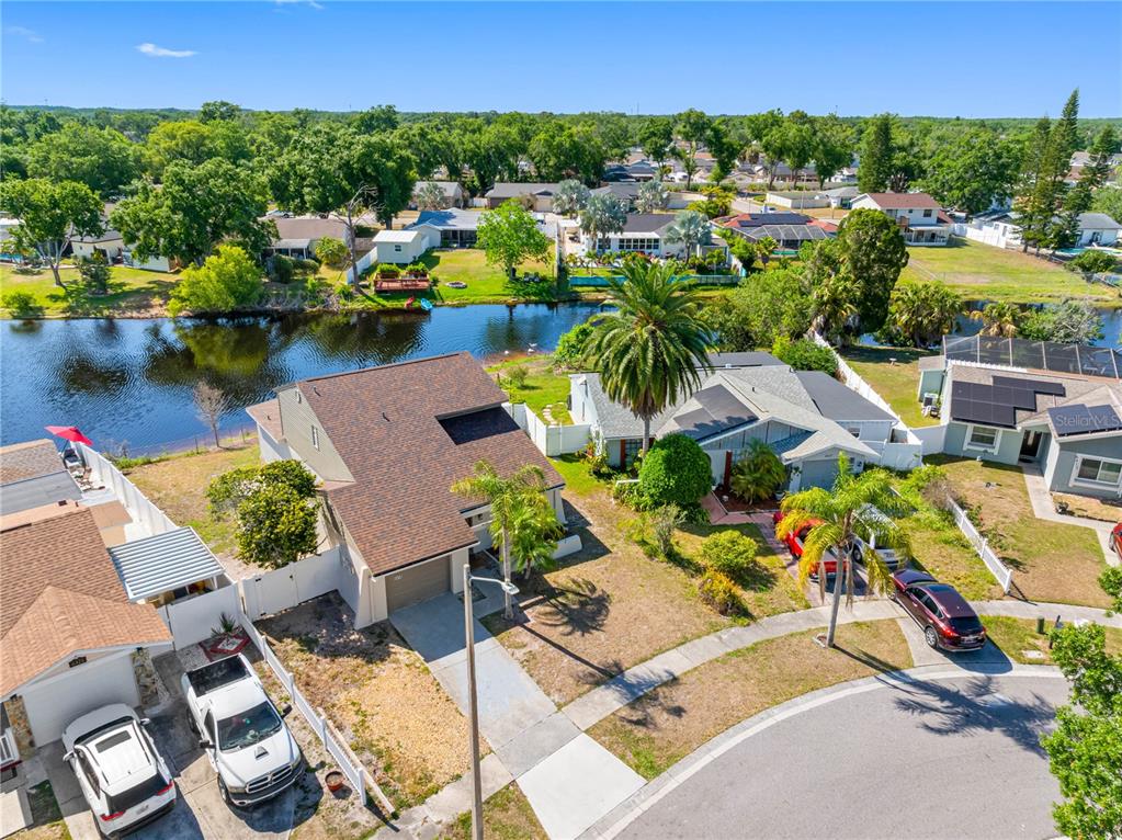 An aerial view shows suburban houses with driveways and lawns bordering a small lake — 6419 MONTEREY BOULEVARD, TAMPA, FL