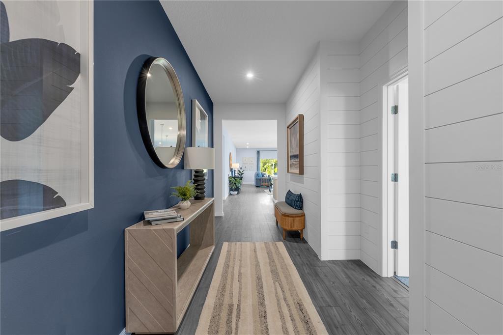 A hallway features a blue accent wall, white shiplap, a console table, and wood flooring — 3836 RISING TRAIL, DAVENPORT, FL
