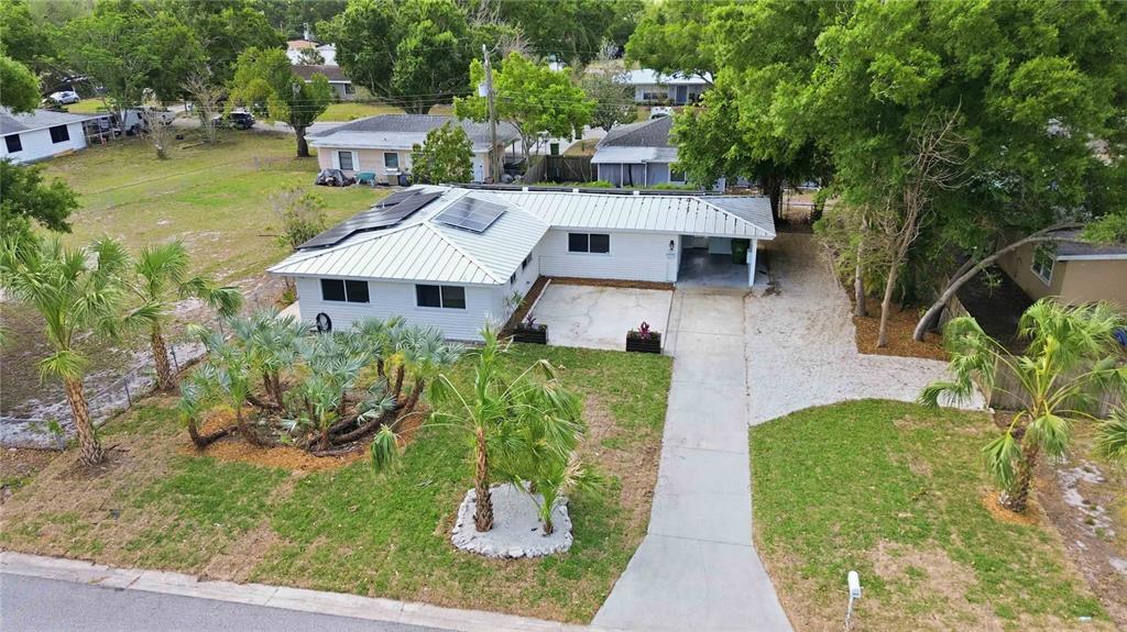 An aerial view shows a white single-story house with a metal roof and solar panels — 2816 MICHIGAN STREET, SARASOTA, FL
