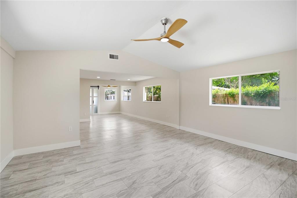 An open-concept living area features light-colored tile flooring, vaulted ceilings, and a modern ceiling fan — 2816 MICHIGAN STREET, SARASOTA, FL