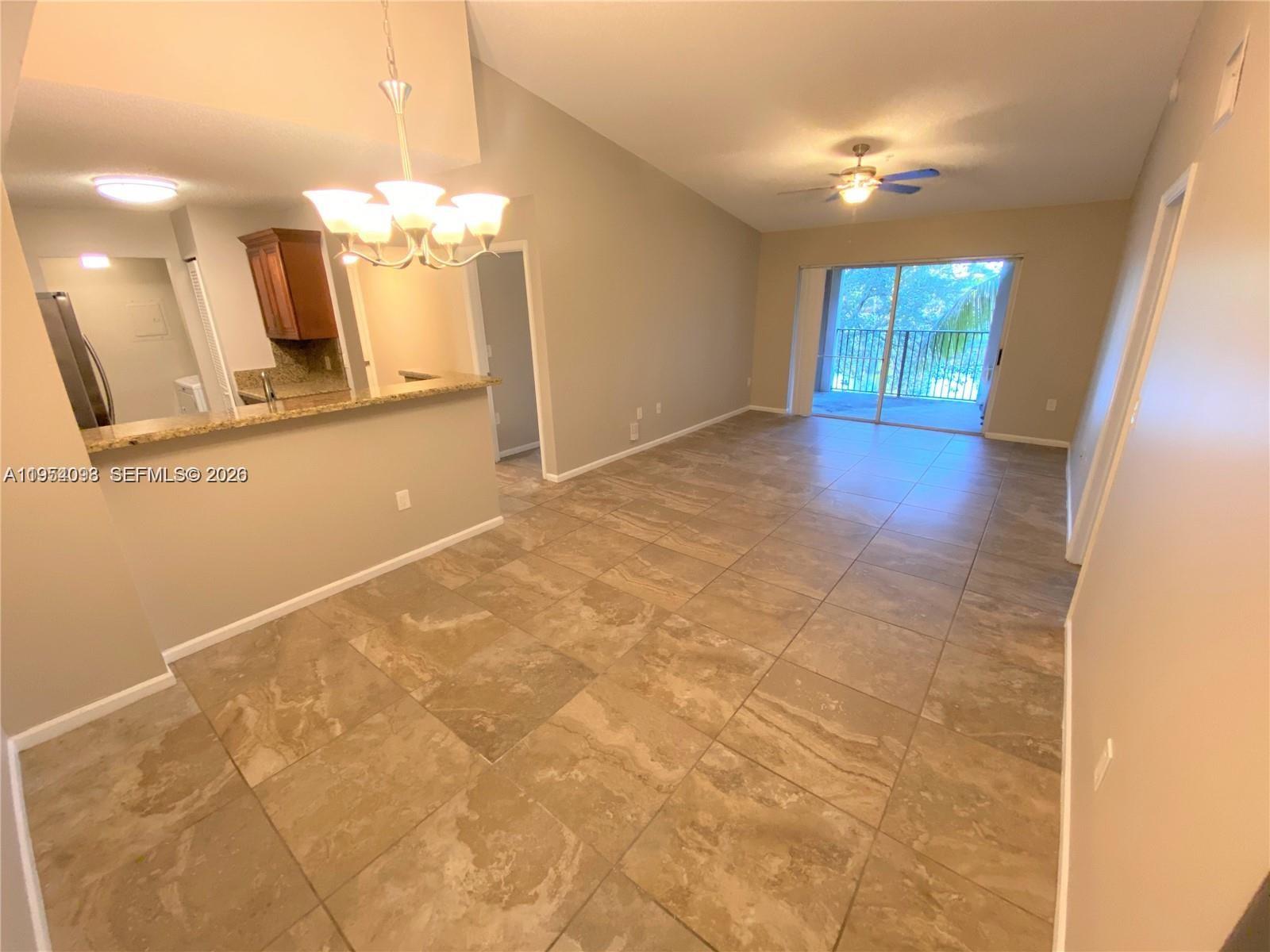 An open-concept living and dining area features large beige floor tiles and a balcony view — 2133 Renaissance Blvd # 306, Miramar FL 33025, MIRAMAR, FL