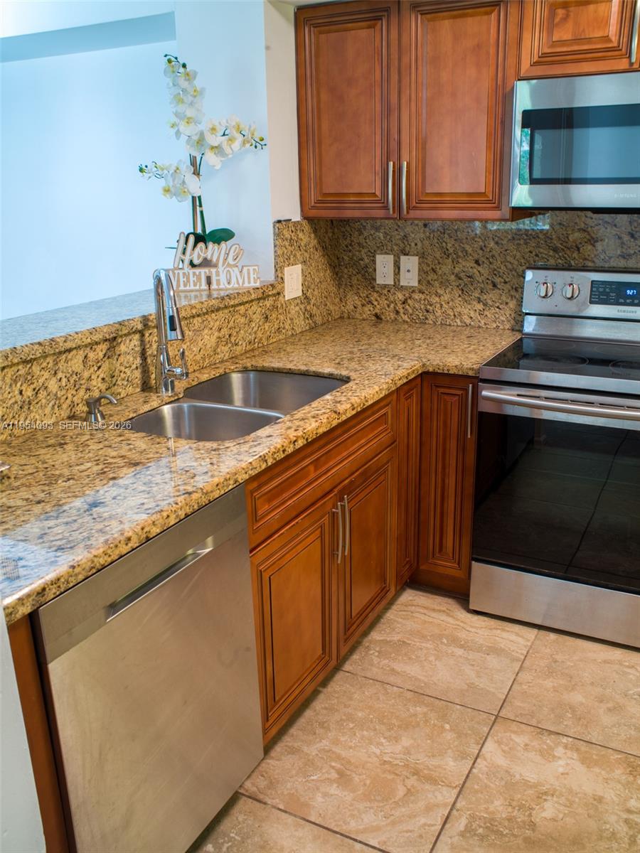A kitchen features granite countertops, wood cabinets, stainless steel appliances, and a double sink — 2133 Renaissance Blvd # 306, Miramar FL 33025, MIRAMAR, FL