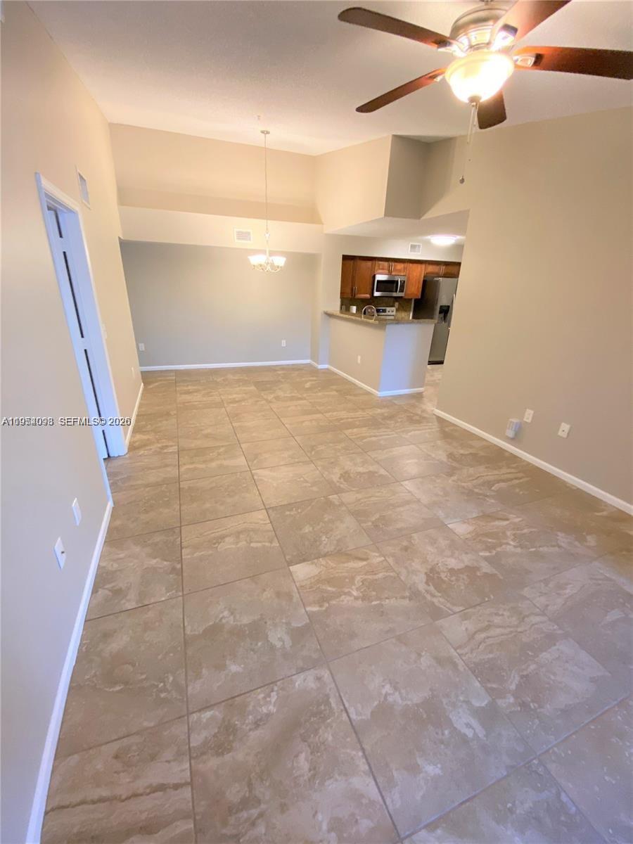 An open-concept dining area features large beige floor tiles and a view of the kitchen — 2133 Renaissance Blvd # 306, Miramar FL 33025, MIRAMAR, FL
