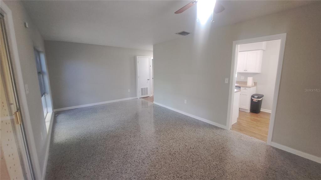 An interior view of a room with light gray walls, terrazzo flooring, and a doorway — 5329 SATEL DRIVE, ORLANDO, FL
