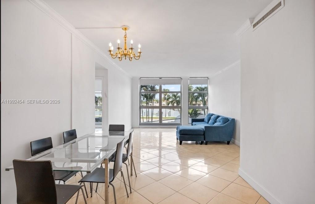 A dining area and living space with tile floors, a chandelier, and large windows — 5055 Collins Ave # 2K, Miami Beach FL 33140, MIAMI BEACH, FL