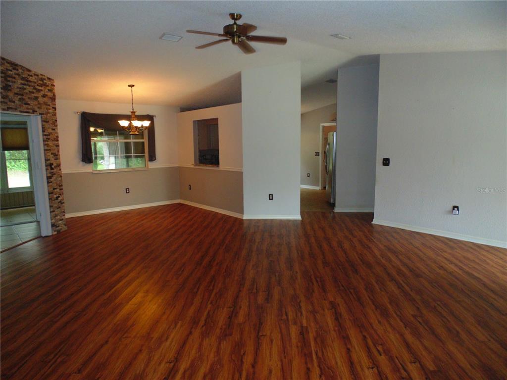 An open-concept living and dining area features wood-look flooring and a ceiling fan — 8125 SW 108 LOOP, OCALA, FL