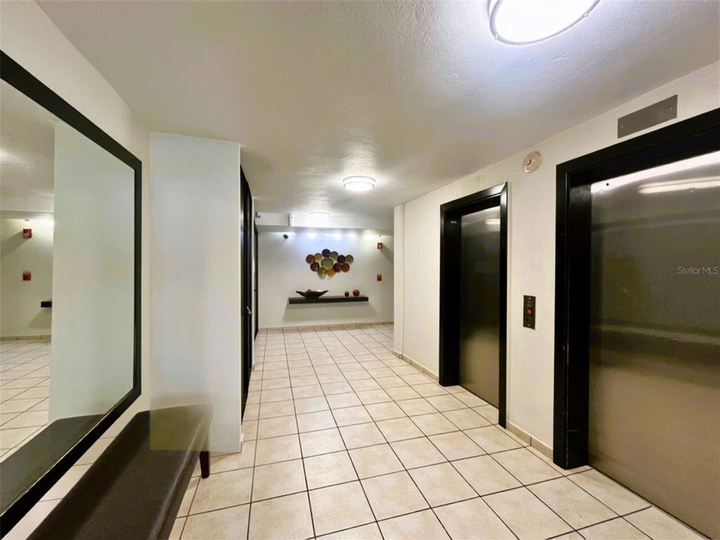 A tiled hallway features a large mirror, a bench, and two elevator doors — 1812 ALCALA UNIT 2301, SAN JUAN, PR